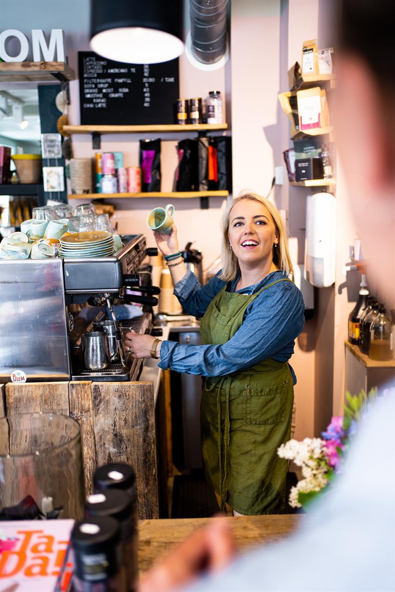kvinne som lager kaffe mens hun snakker med en kunde
