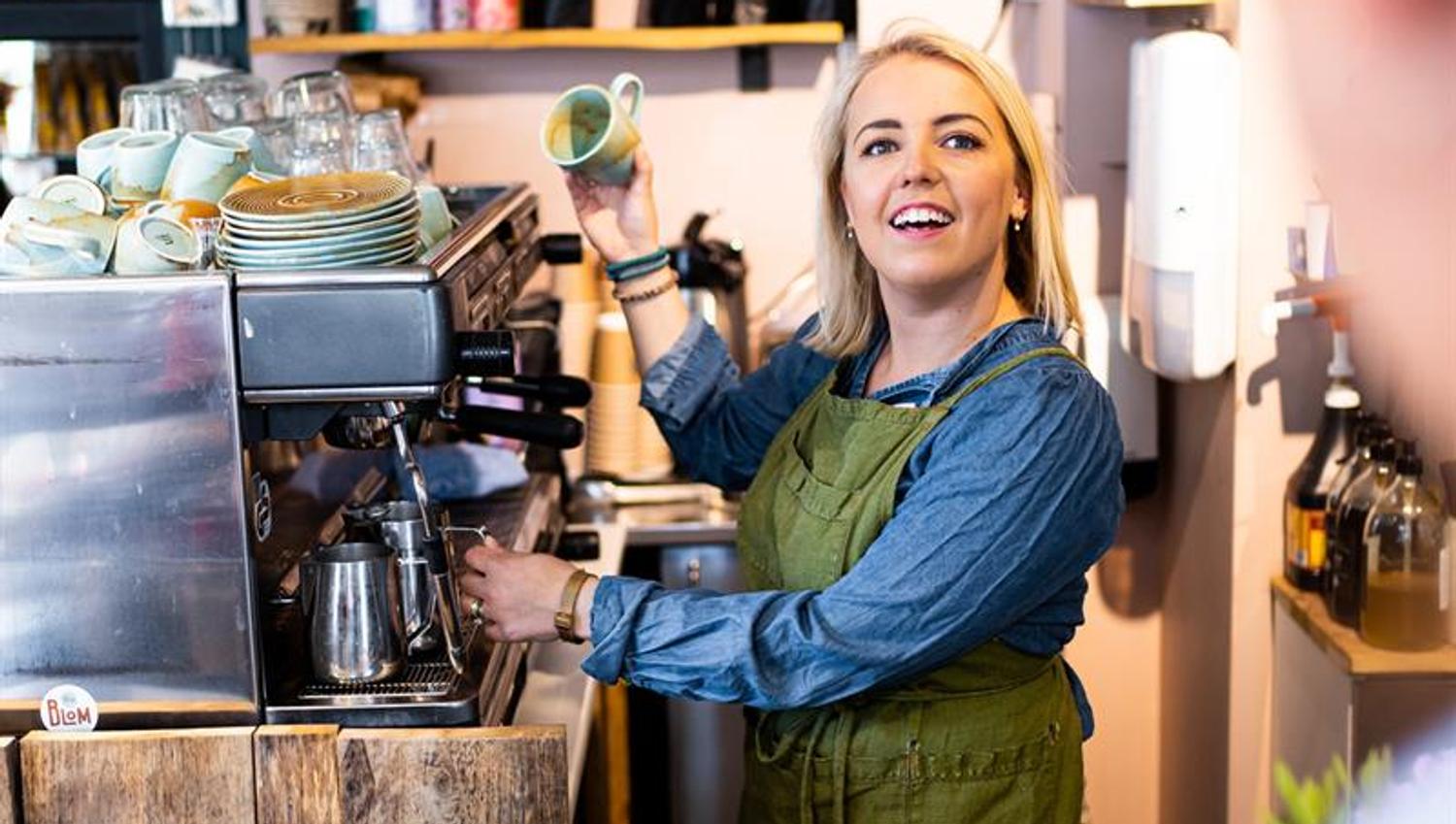kvinne som lager kaffe mens hun snakker med en kunde