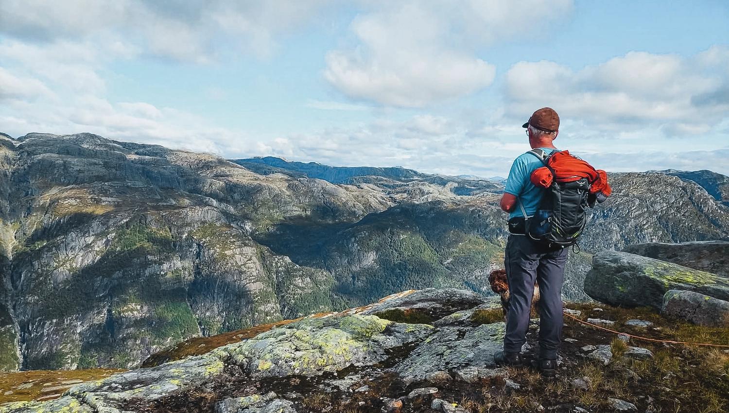Hiker with backpack enjoying panoramic mountain views in Hardanger, Norway, a prime destination for hiking