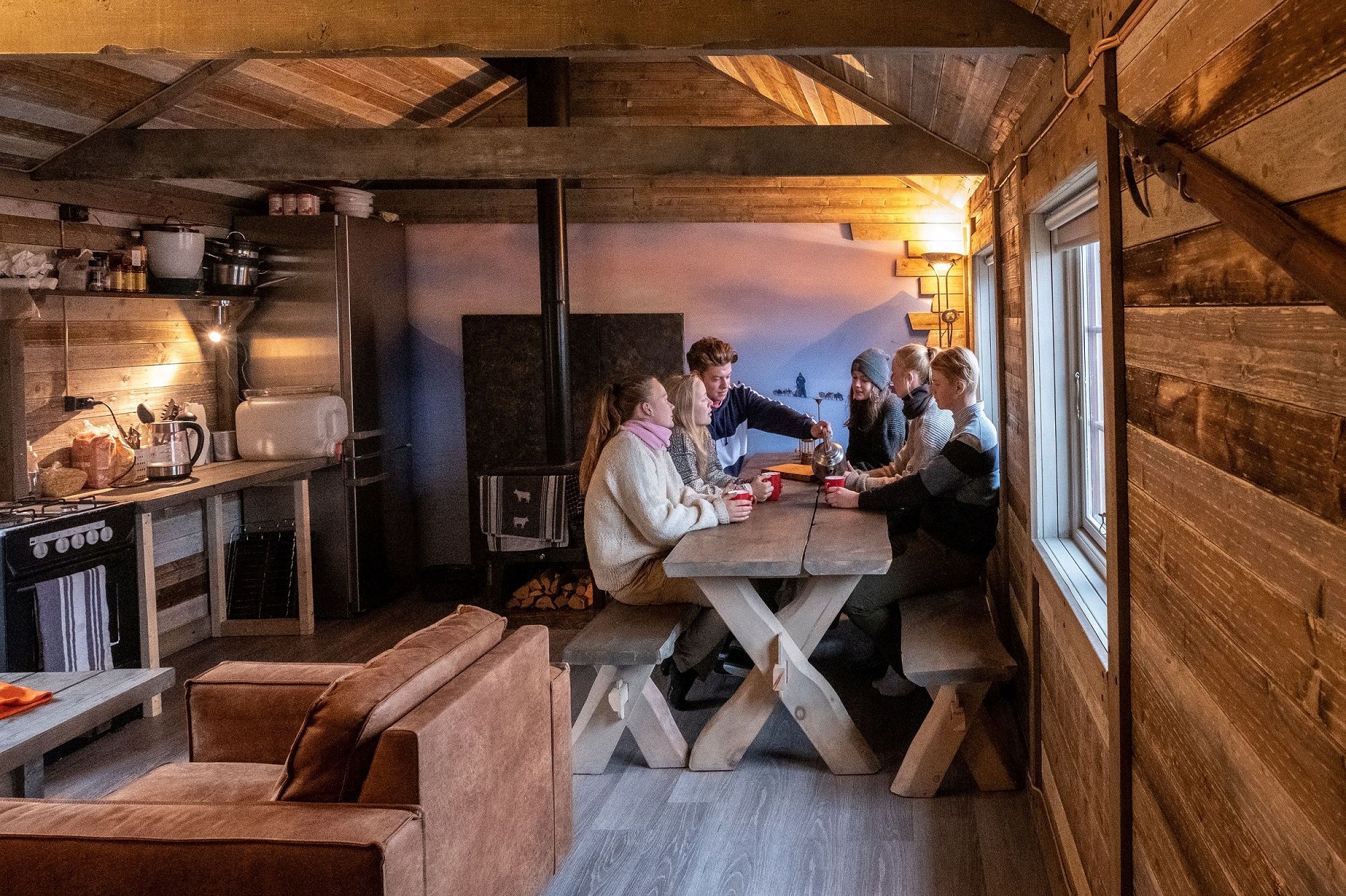 A group of guests sitting around a table in the living room at Tommy's Lodge