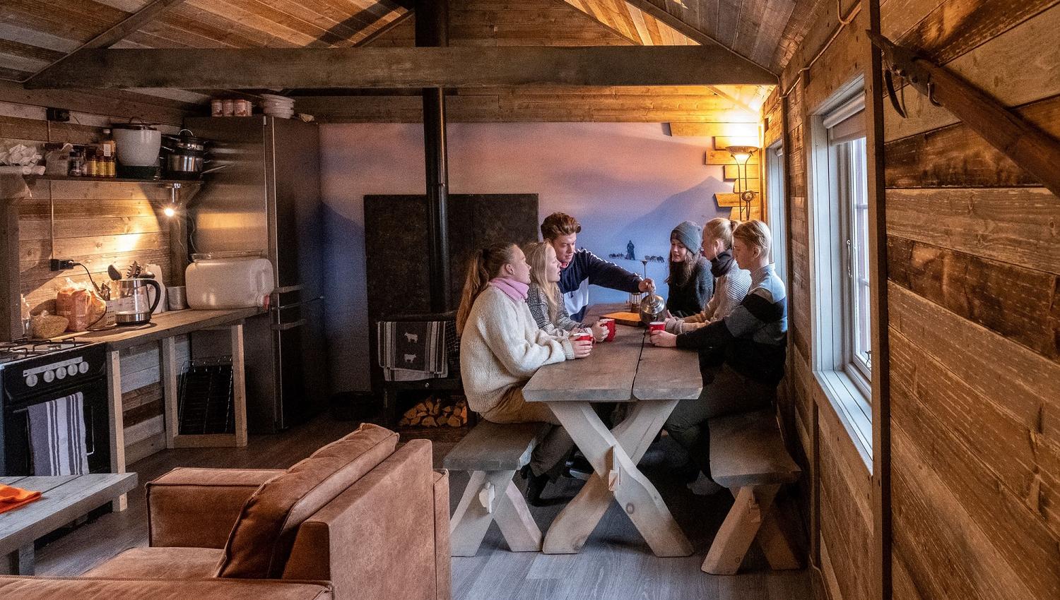 A group of guests sitting around a table in the living room at Tommy's Lodge