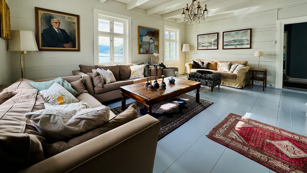 Cozy living room at Kramsjø Guesthouse with fjord view, classic interior, and artwork on the walls.