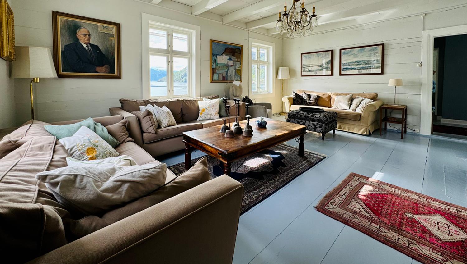 Cozy living room at Kramsjø Guesthouse with fjord view, classic interior, and artwork on the walls.