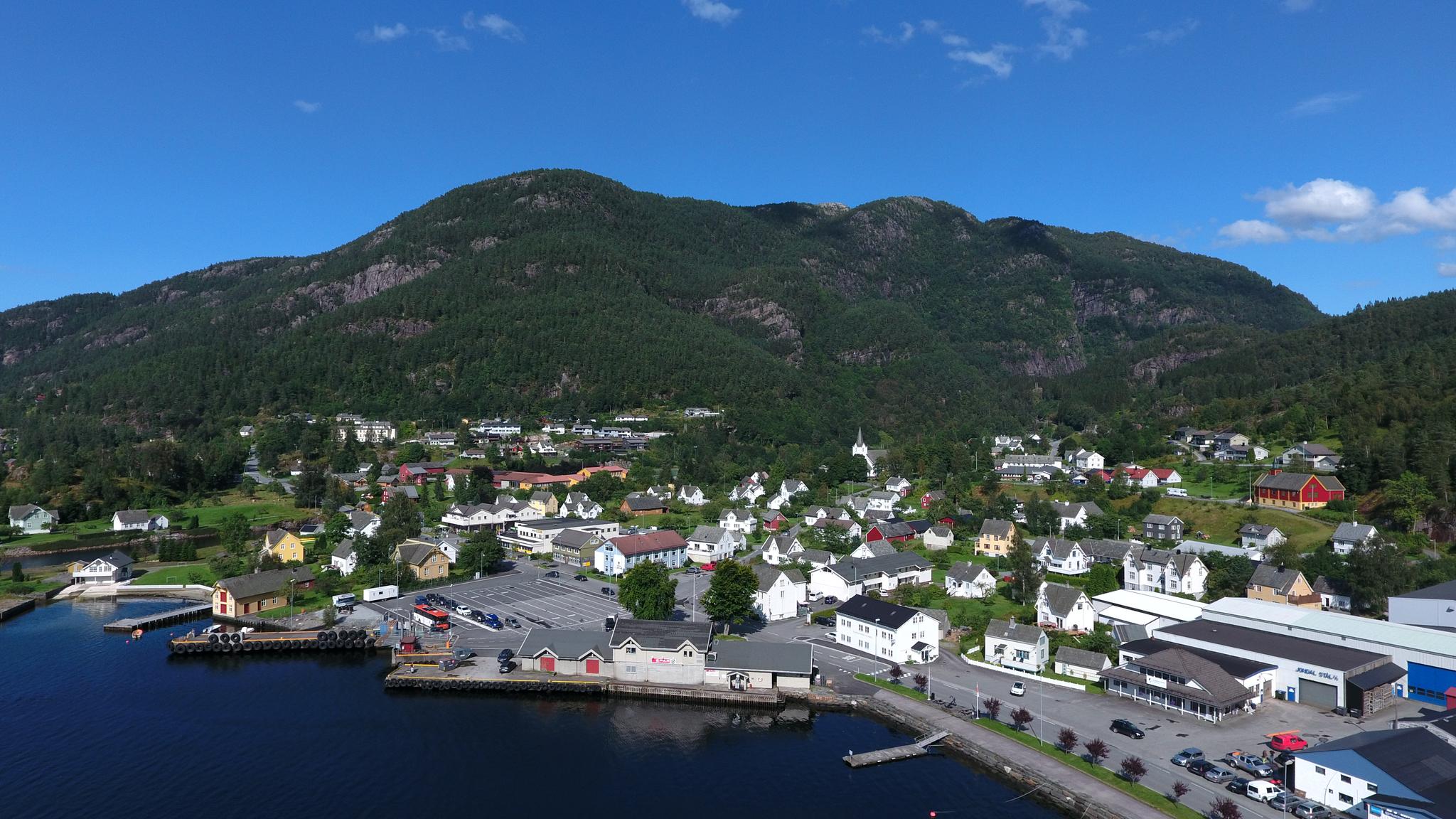Aerial view of Jondal village in Hardanger – a charming fjord community surrounded by mountains and greenery, with SPAR Jondal located by the waterfro