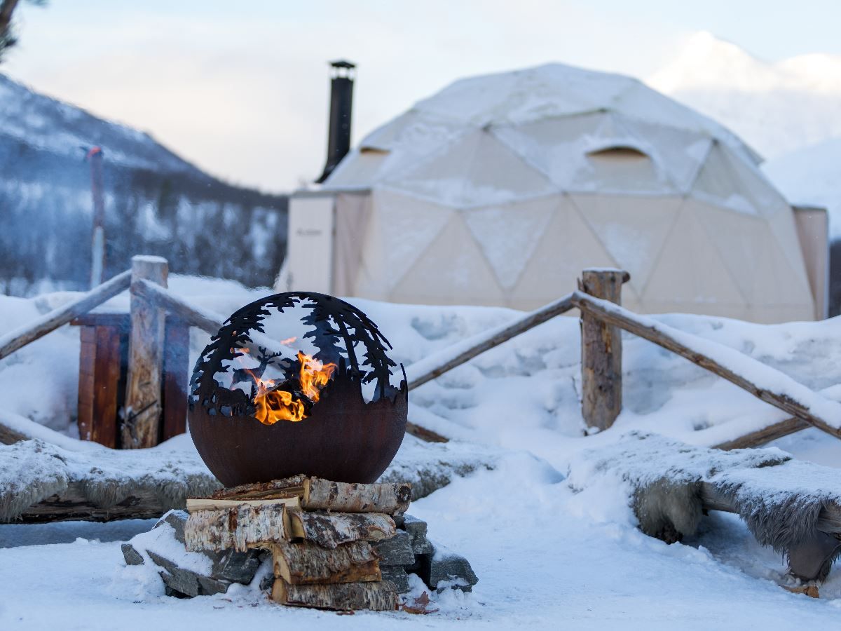 Campfire in front of a lavvu in the winter landscape at Camp Tamok