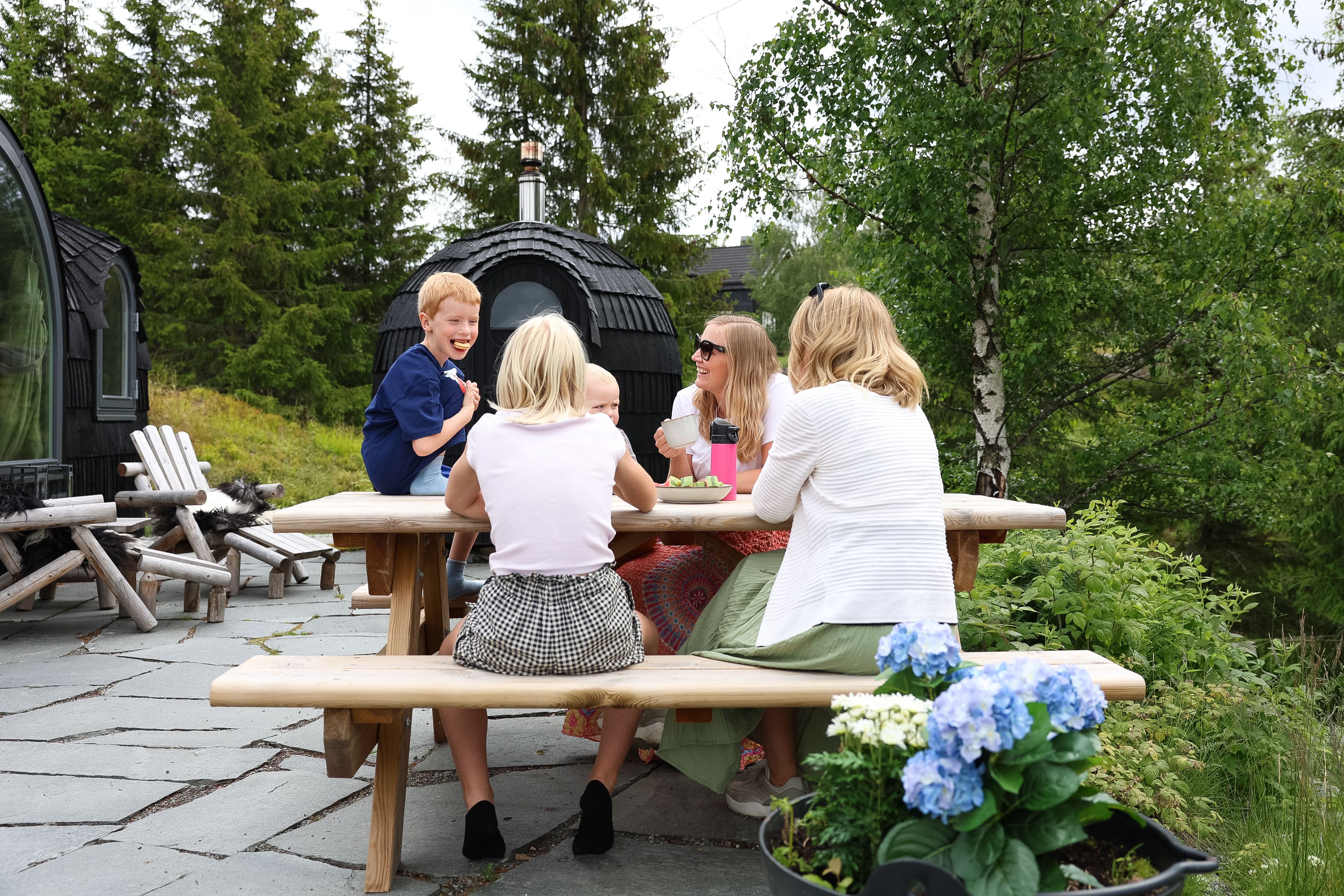 Gruppe som sitter ved et piknikbord ute i naturen ved en grillhytte