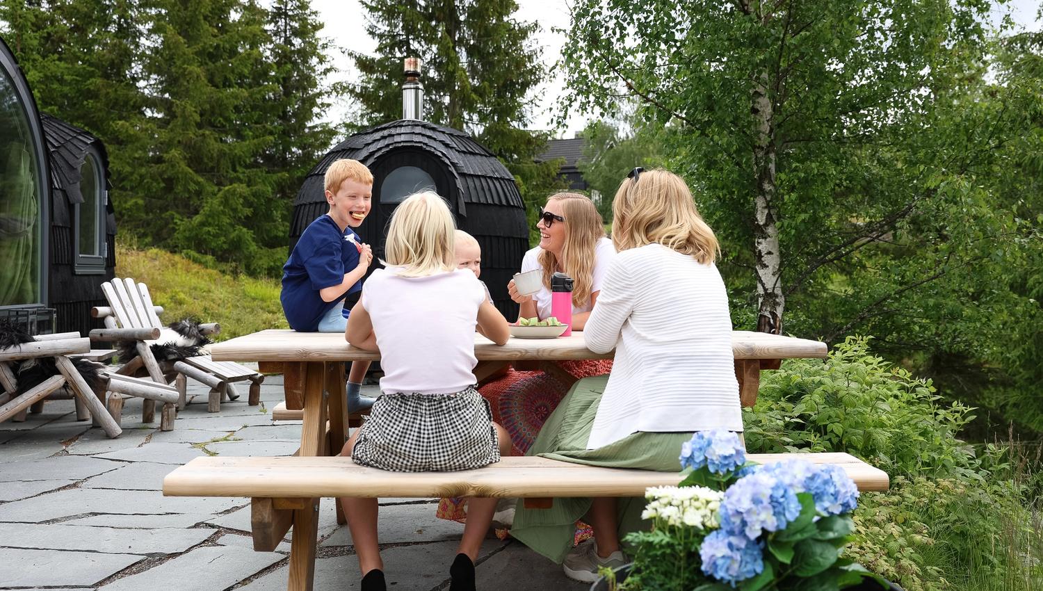 Gruppe som sitter ved et piknikbord ute i naturen ved en grillhytte