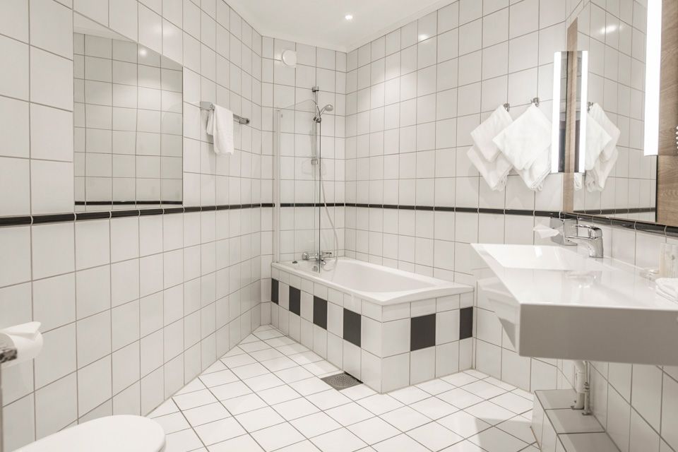 Bad, interiør med hvite fliser og hvitt møblement. Hotell Bondeheimen, Oslo. Foto