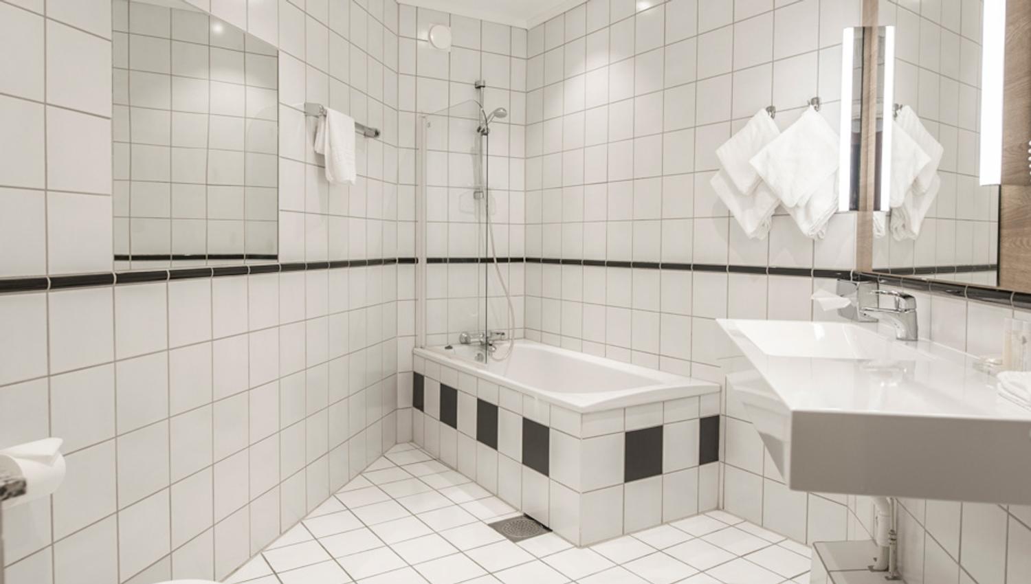 Bad, interiør med hvite fliser og hvitt møblement. Hotell Bondeheimen, Oslo. Foto