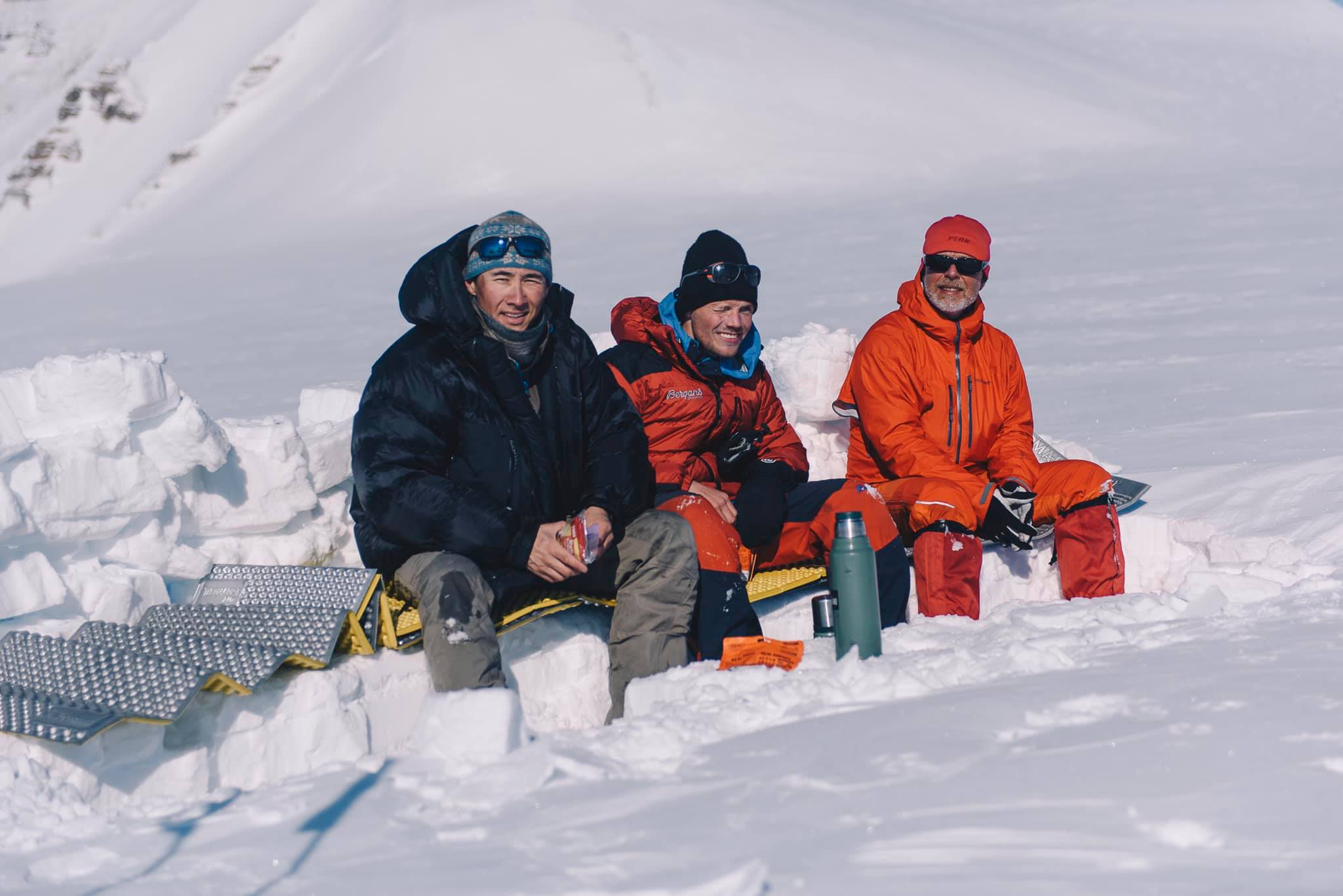 Three persons sitting in the snow
