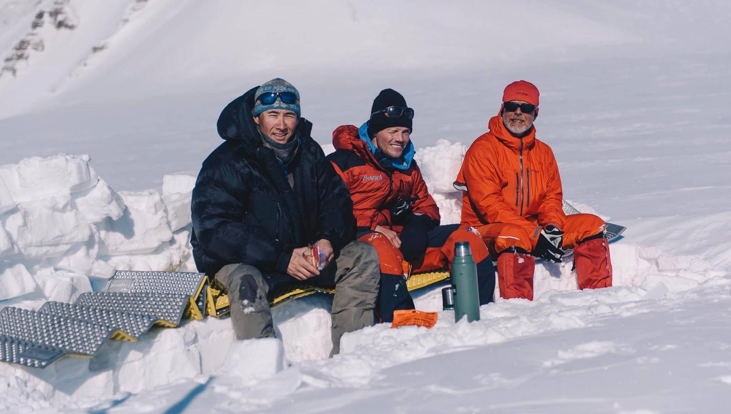 Three persons sitting in the snow