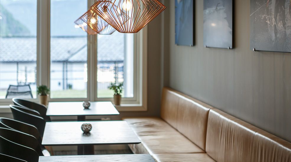 A long leather sofa, small tables and chairs on the opposite side.