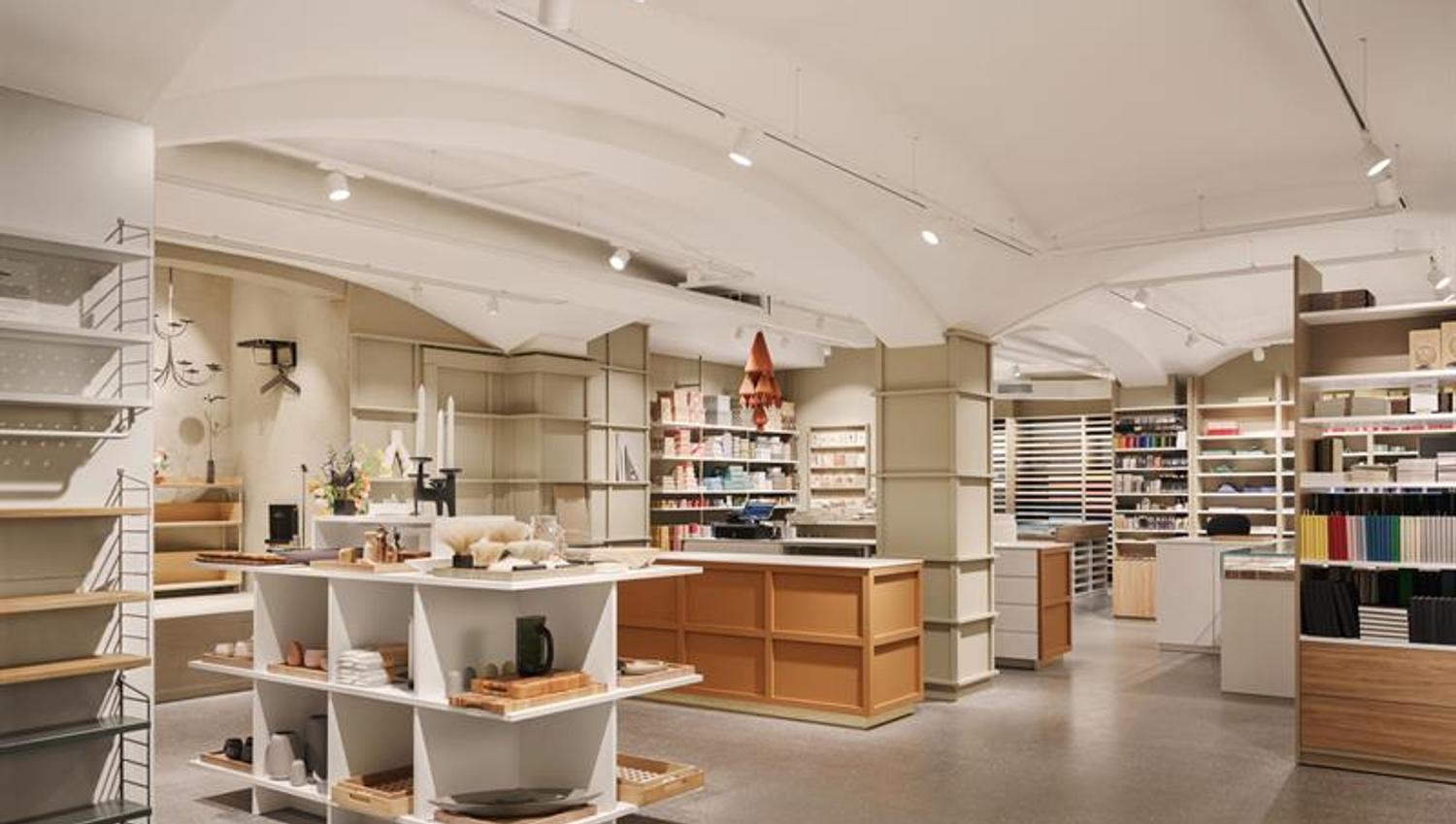 Butikkinteriør. Hvitt tak, grå gulv, beige vegger, hyller med en rekke forskjellige produkter.