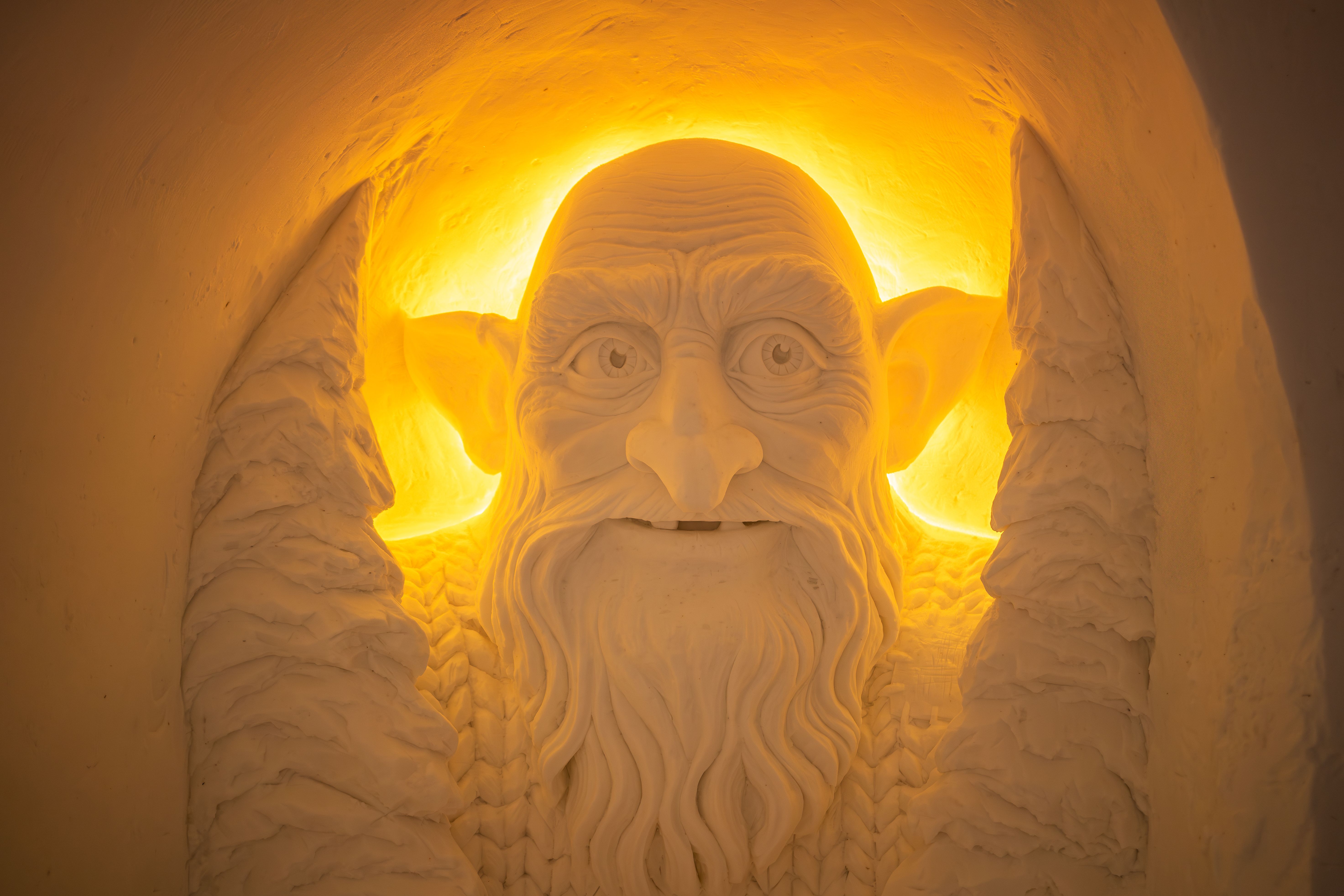 Ontdek deze indrukwekkende sneeuwsculptuur van een wijze oude man, omringd door een warme gloed. Deze kunstwerk toont de vaardigheid van de kunstenaars en creëert een betoverende sfeer die je meeneemt naar een magische wereld.