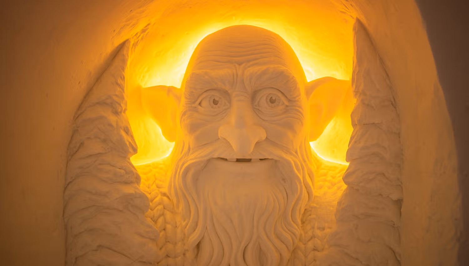 Ontdek deze indrukwekkende sneeuwsculptuur van een wijze oude man, omringd door een warme gloed. Deze kunstwerk toont de vaardigheid van de kunstenaars en creëert een betoverende sfeer die je meeneemt naar een magische wereld.