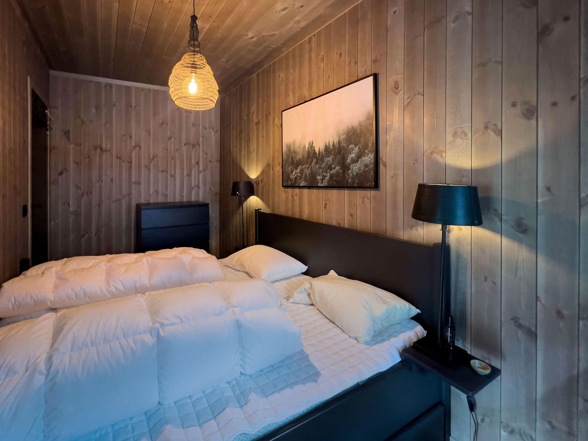Ein Bett mit weißen Laken und einer Lampe in einem Zimmer.