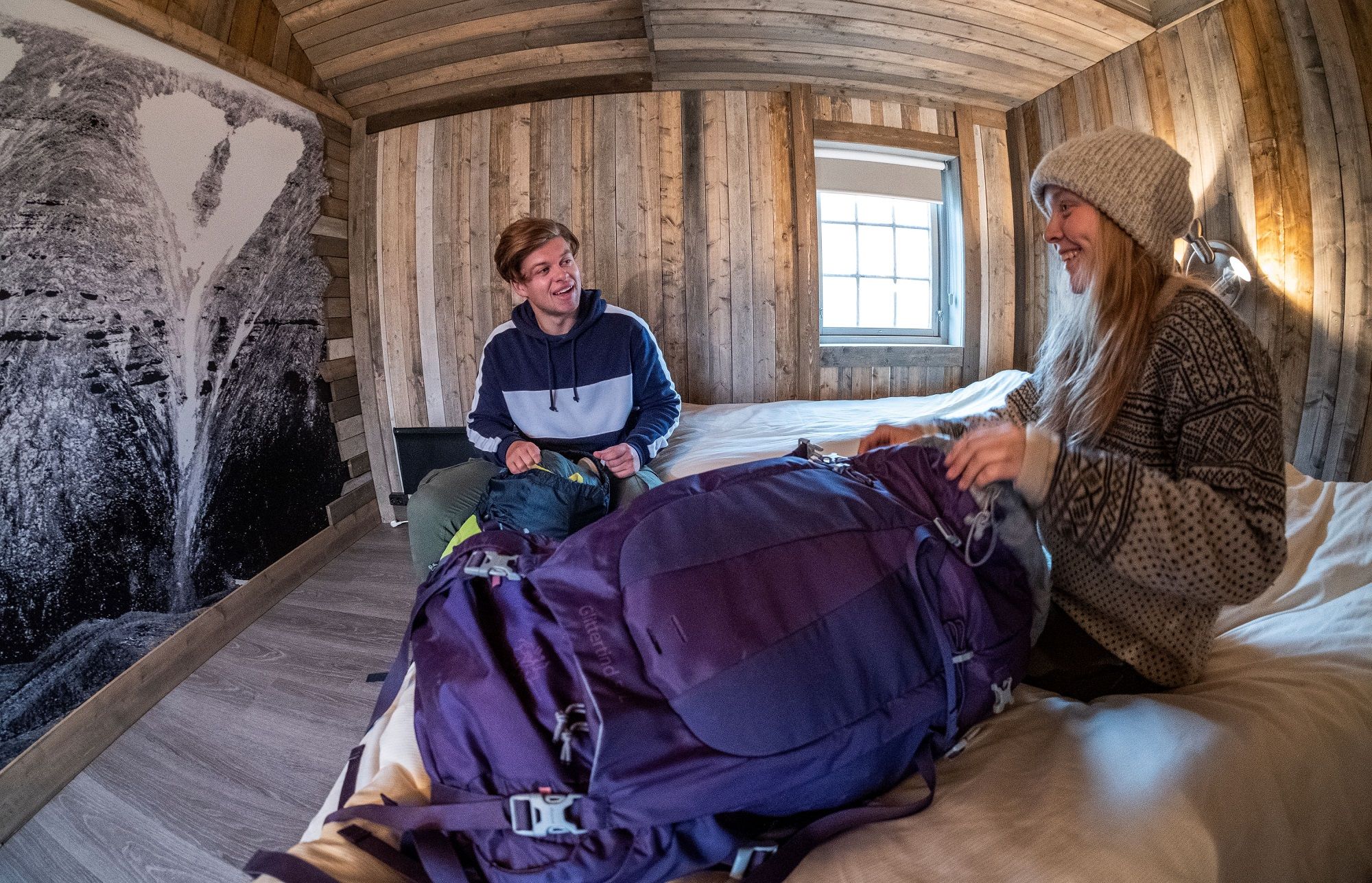 Two guests sitting on two beds inside a bedroom at Tommy's Lodge