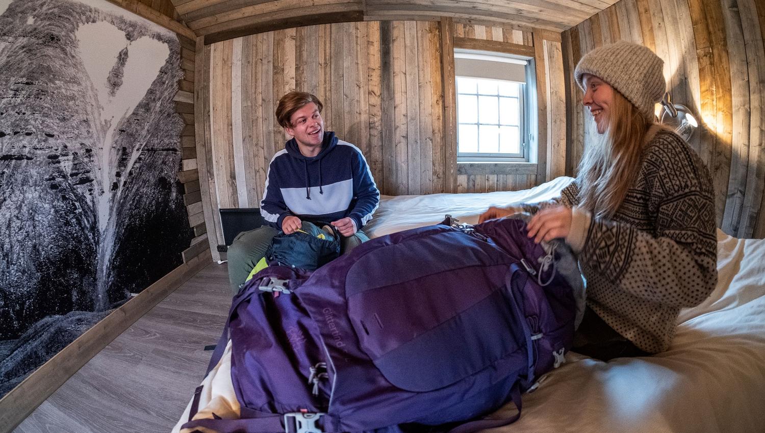 Two guests sitting on two beds inside a bedroom at Tommy's Lodge