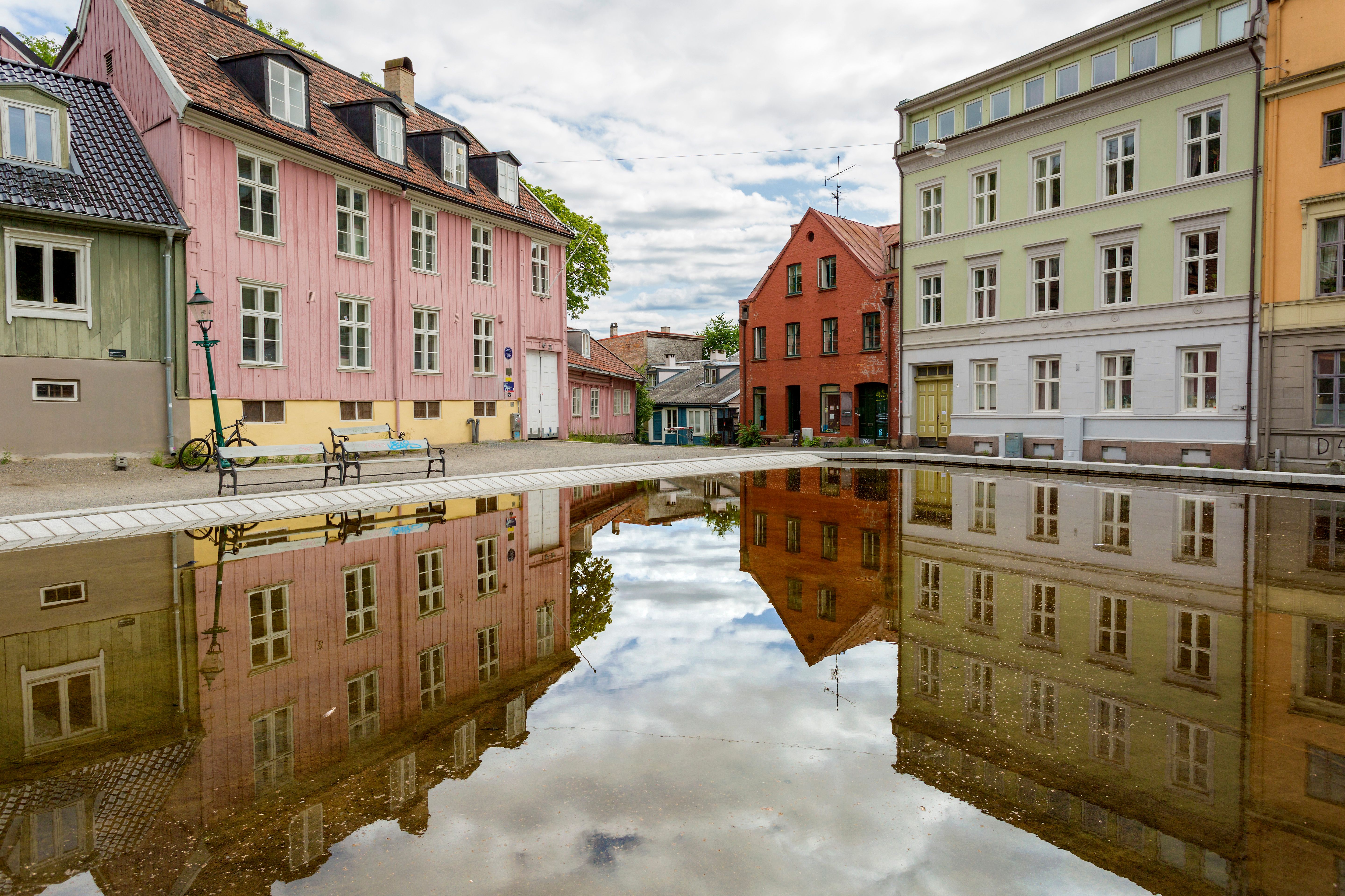Old wooden houses surrounding a square with a pool.