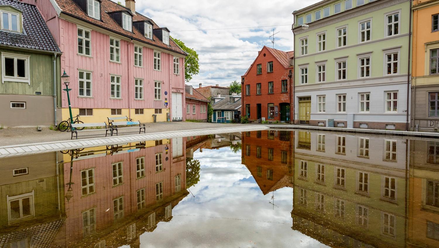 Old wooden houses surrounding a square with a pool.