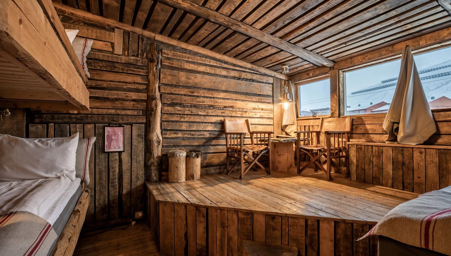 Et hytte inspirert hotellrom, med tre senger, og to stoler.