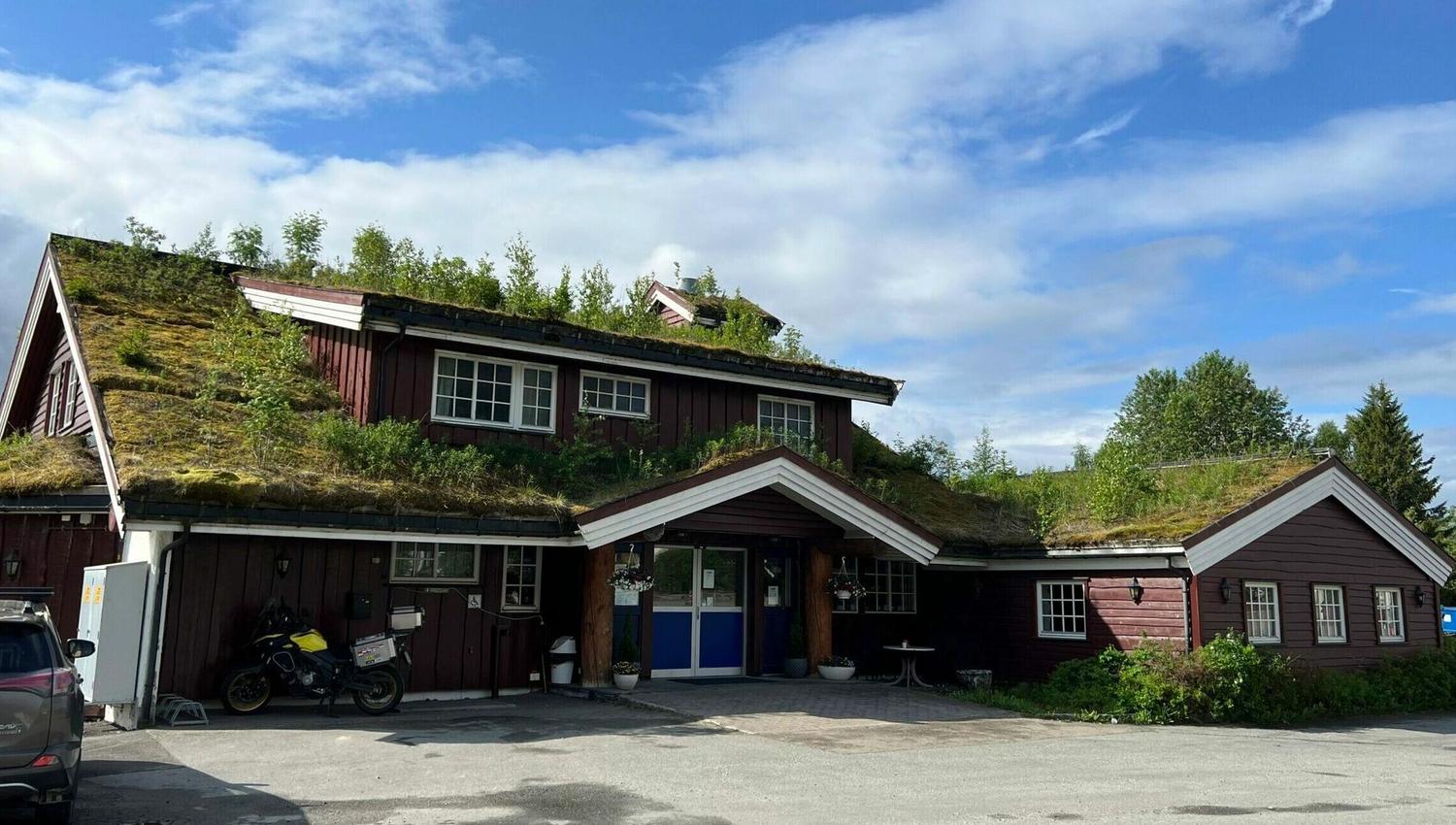 Utsiden av Bimbo veikro, mørkt bygg med torvtak