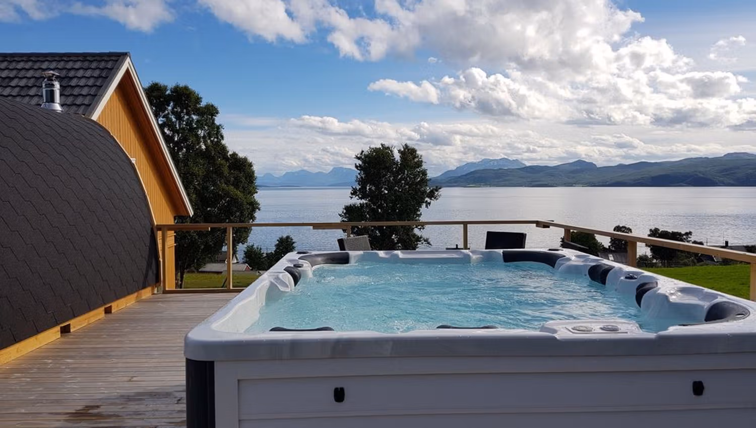 Outdoor hot tub on a terrace with a view of a lake and mountains