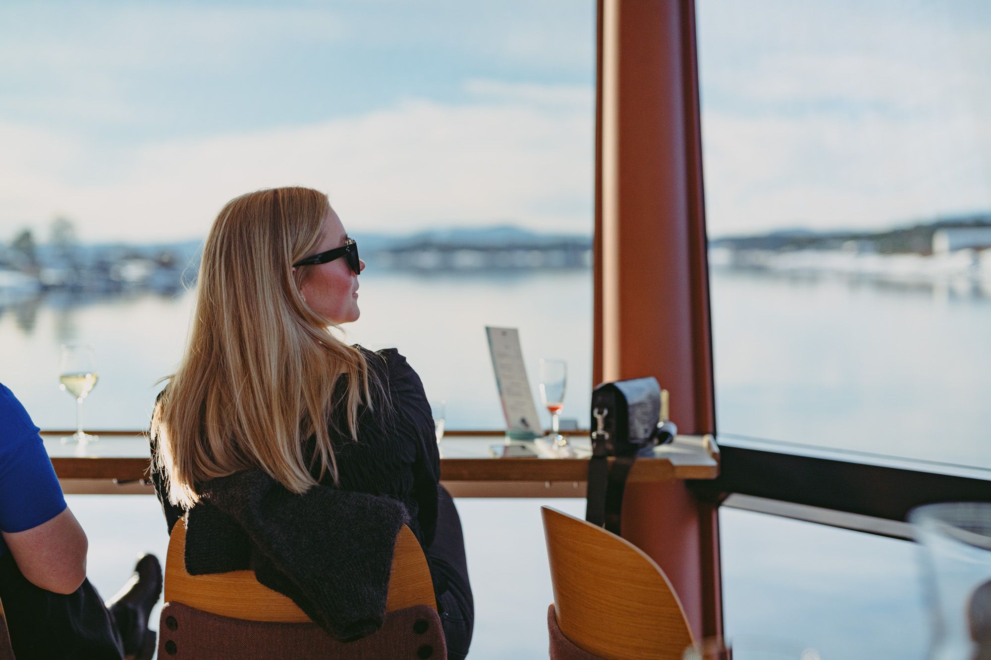 Jente som sitter inne i båten og ser på utsikten gjennom panoramavinduet