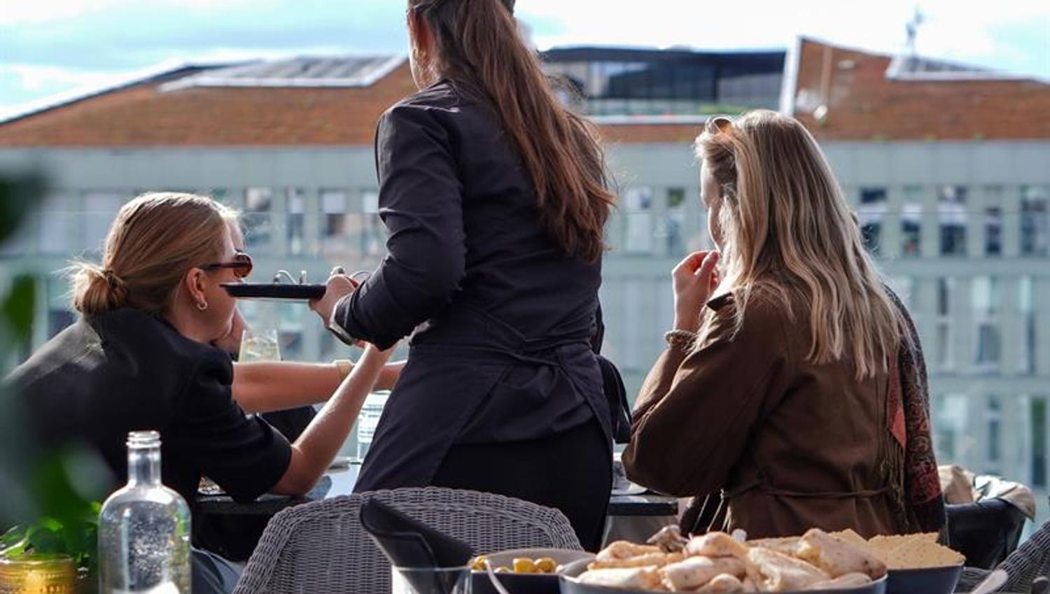 Guests enjoying food and drinks on a sunny rooftop terrace in Oslo.