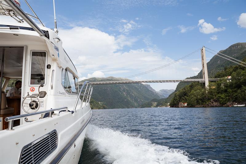 Pilagutt sailing under a bridge in the Hardangerfjord.