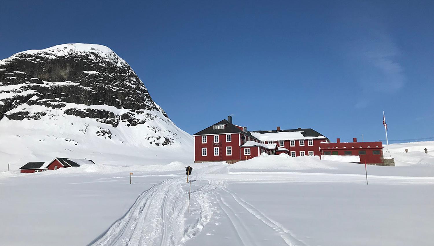 Bygdin Fjellhotell i vinterlandskap. Skiløype rett utenfor døra, og fjellet Bitihorn i bakgrunnen.