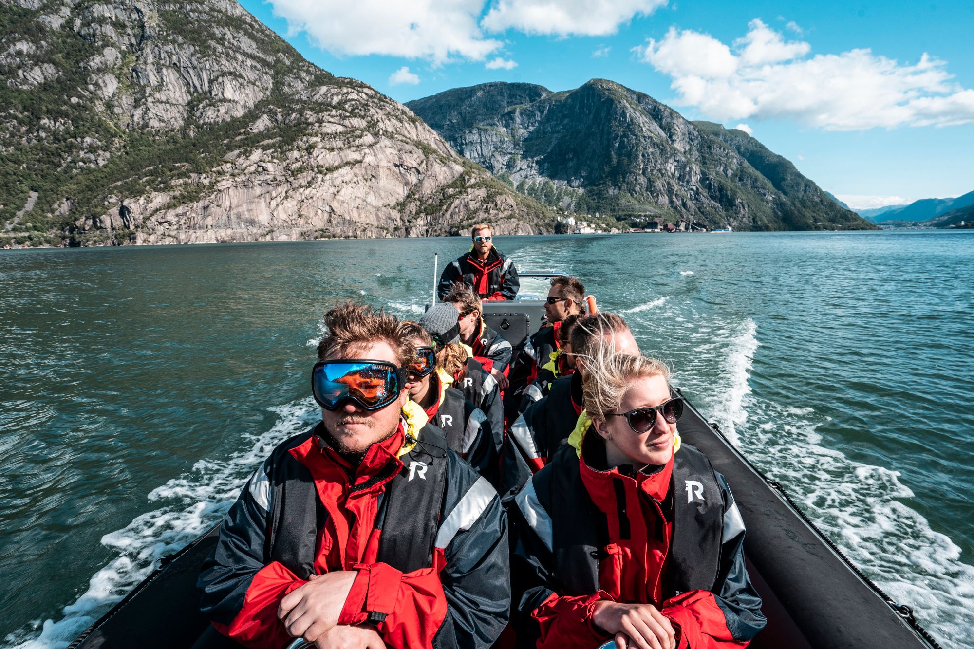 Eventyrlystne turistar på RIB-safari omgitt av rå norsk natur.