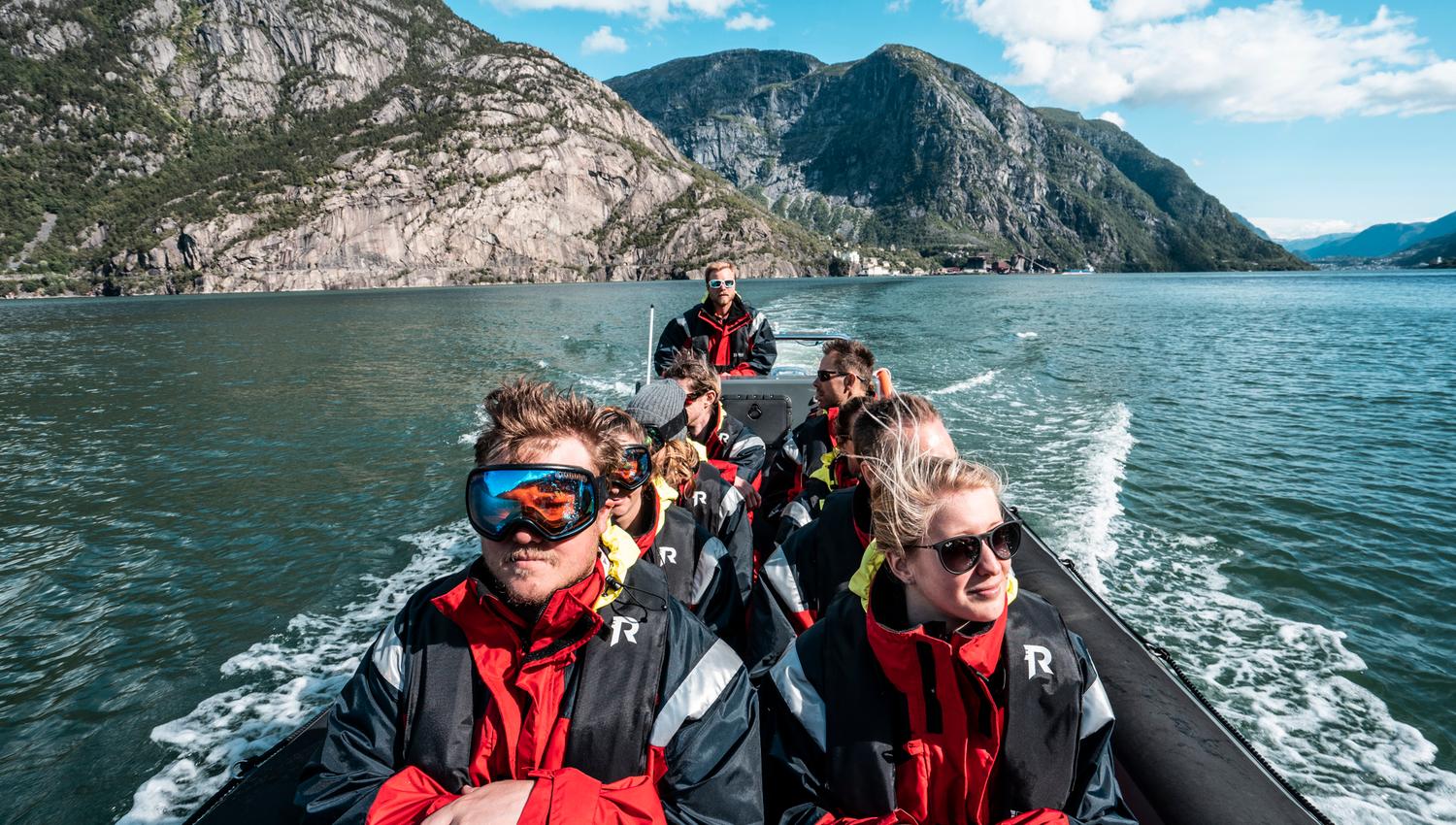 Eventyrlystne turistar på RIB-safari omgitt av rå norsk natur.