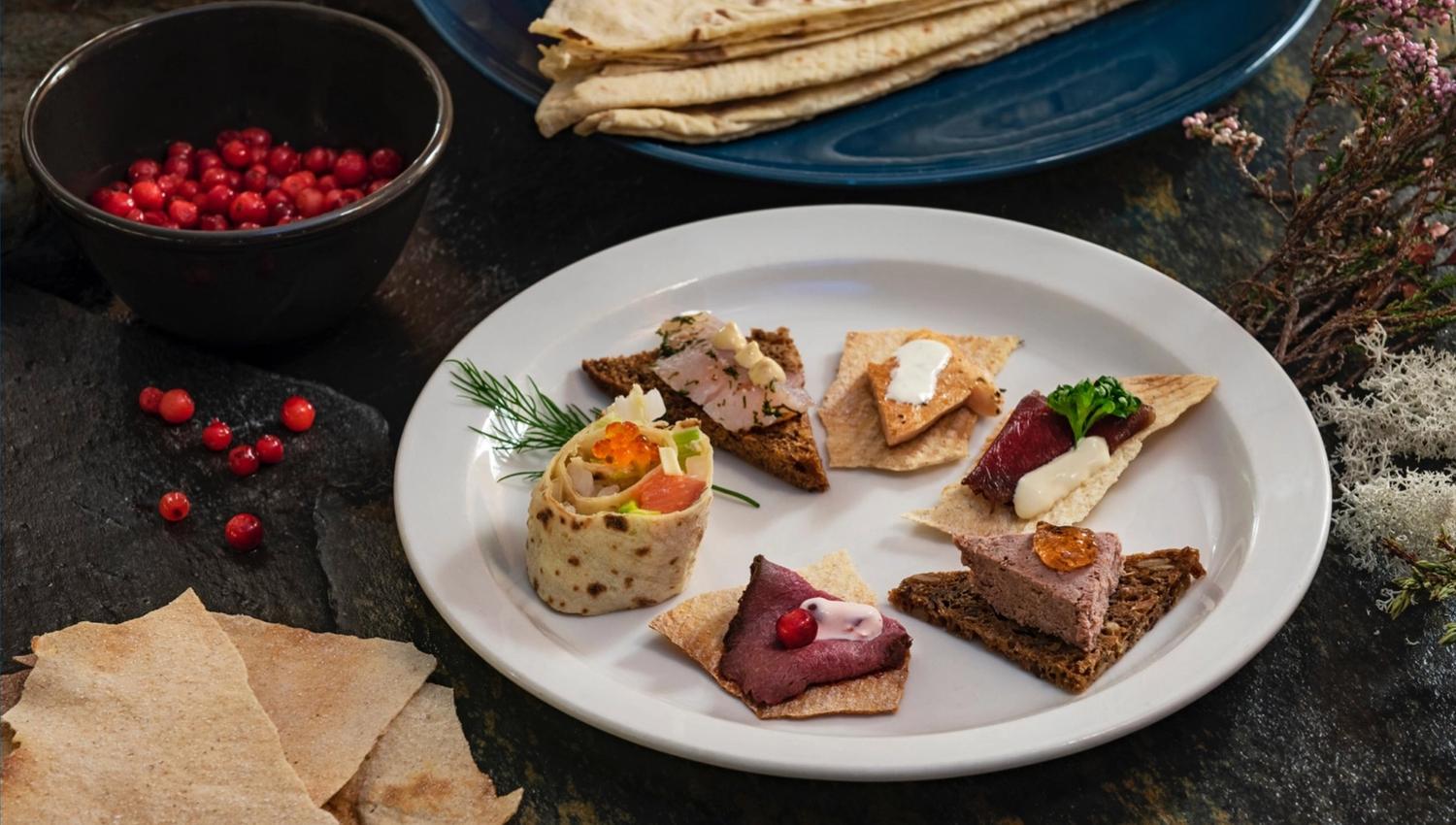 A tasting plate with five pates on toast and a lease roll