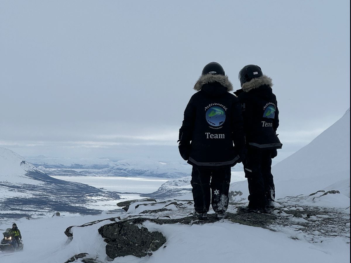 Two guides overlooking the snowy mountain landscape of Skibotn Valley