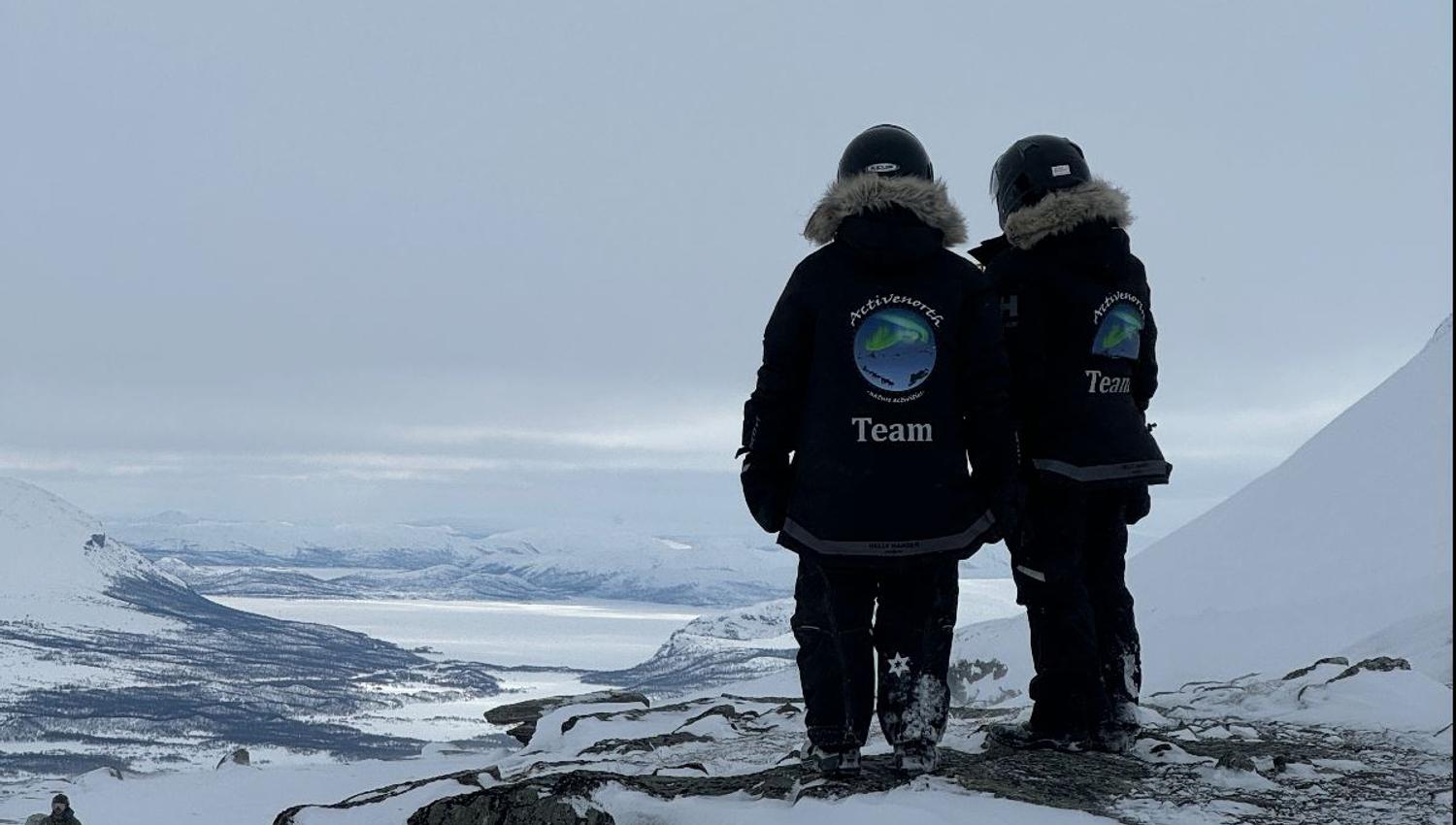 Two guides overlooking the snowy mountain landscape of Skibotn Valley