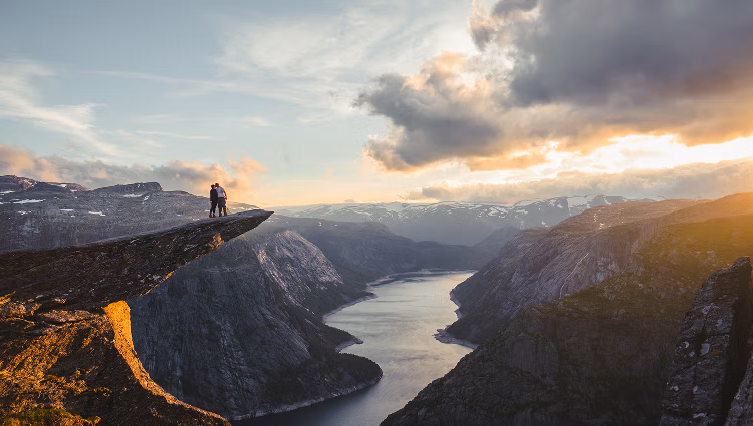 A couple standing on Trolltunga looking over Ringedalsvatnet lake.