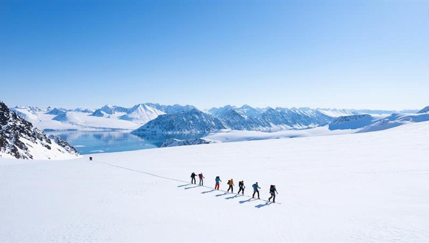En gruppe mennesker går opp et fjell på ski