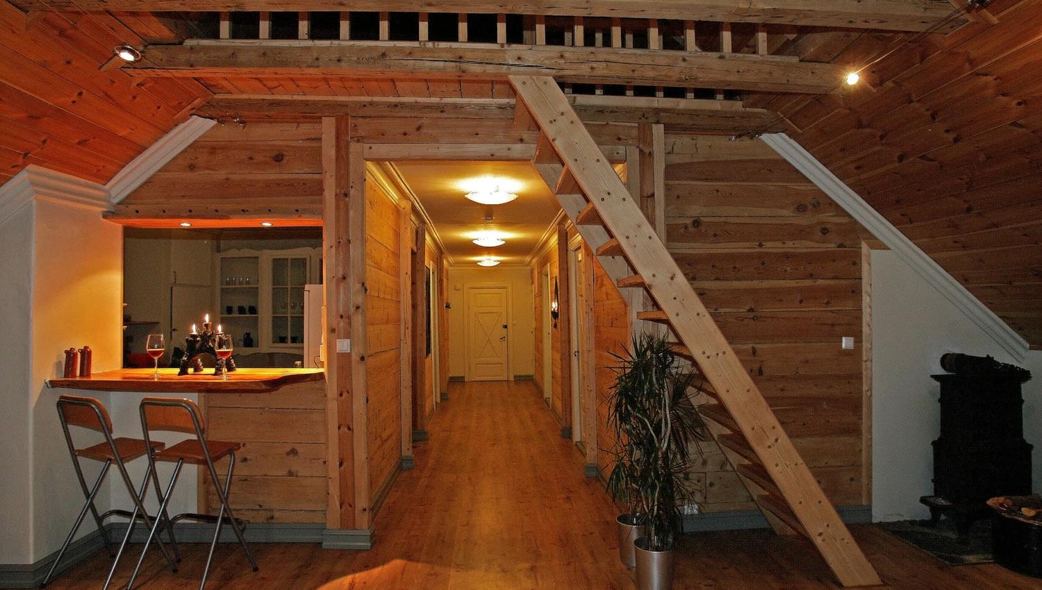 Bright and cozy common area at Vikinghaug Apartments featuring wooden interiors, a small bar and open staircase, perfect for relaxed evenings.