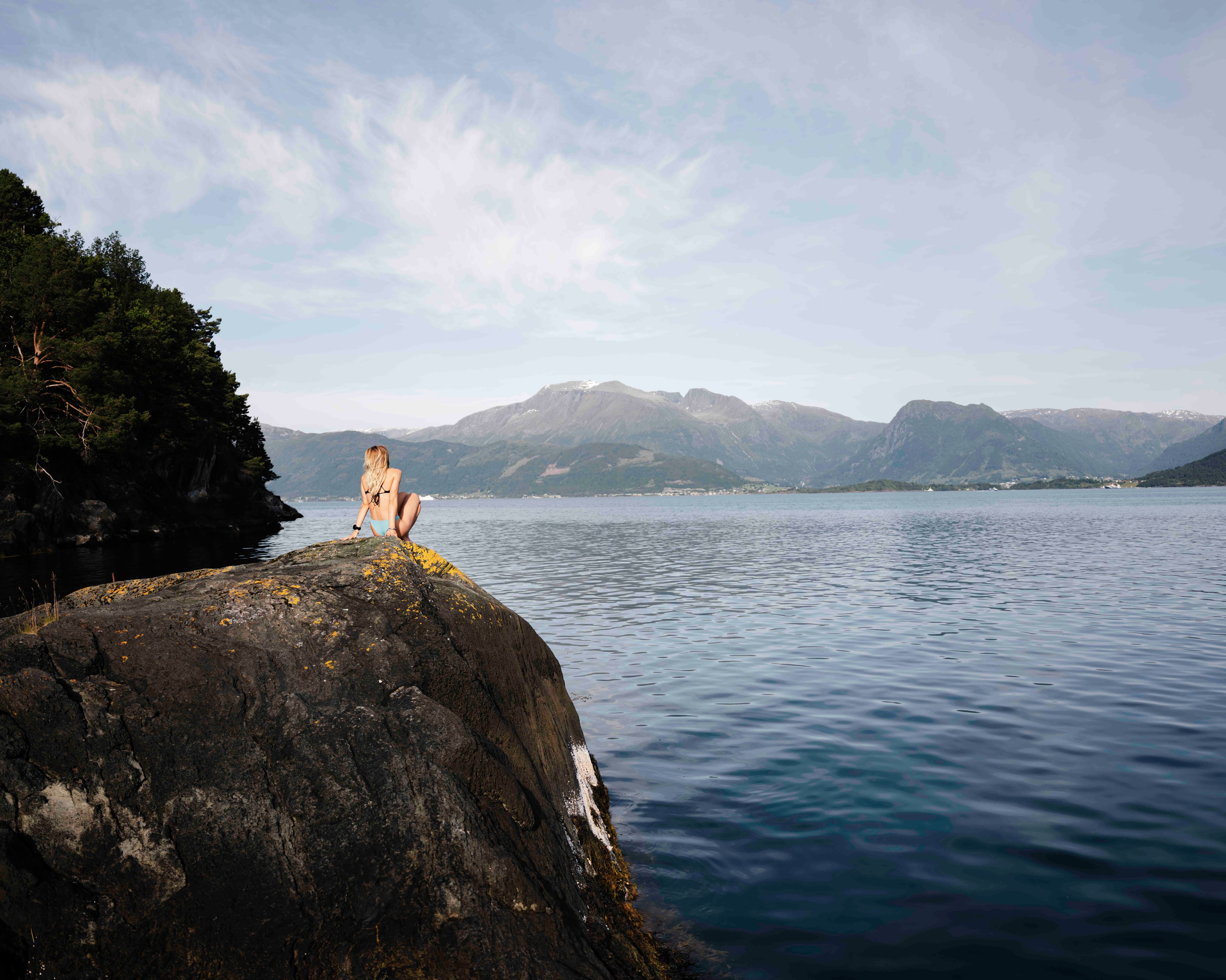 Sitting by the fjord on shoreline rocks with mountain views in Hardanger.