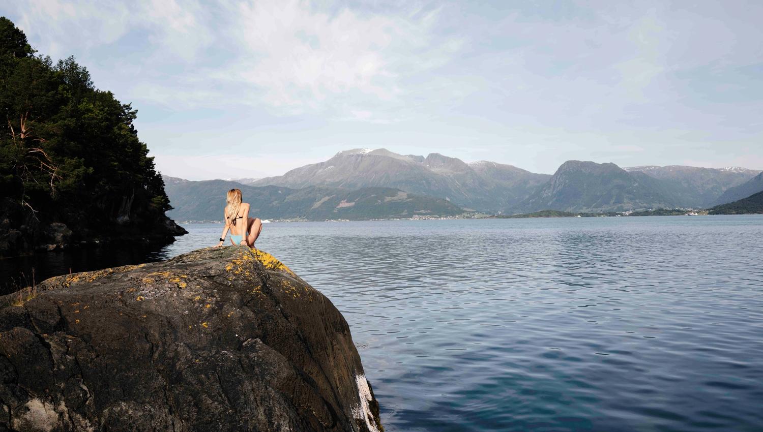 Sitting by the fjord on shoreline rocks with mountain views in Hardanger.