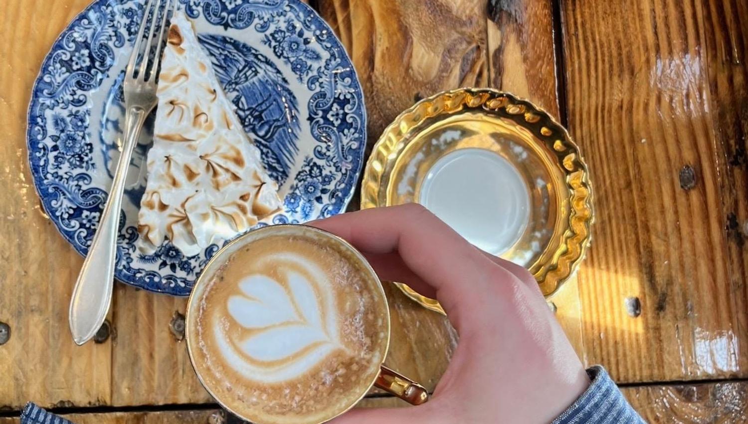 Kaffekopp med latte art og kake på et trebord