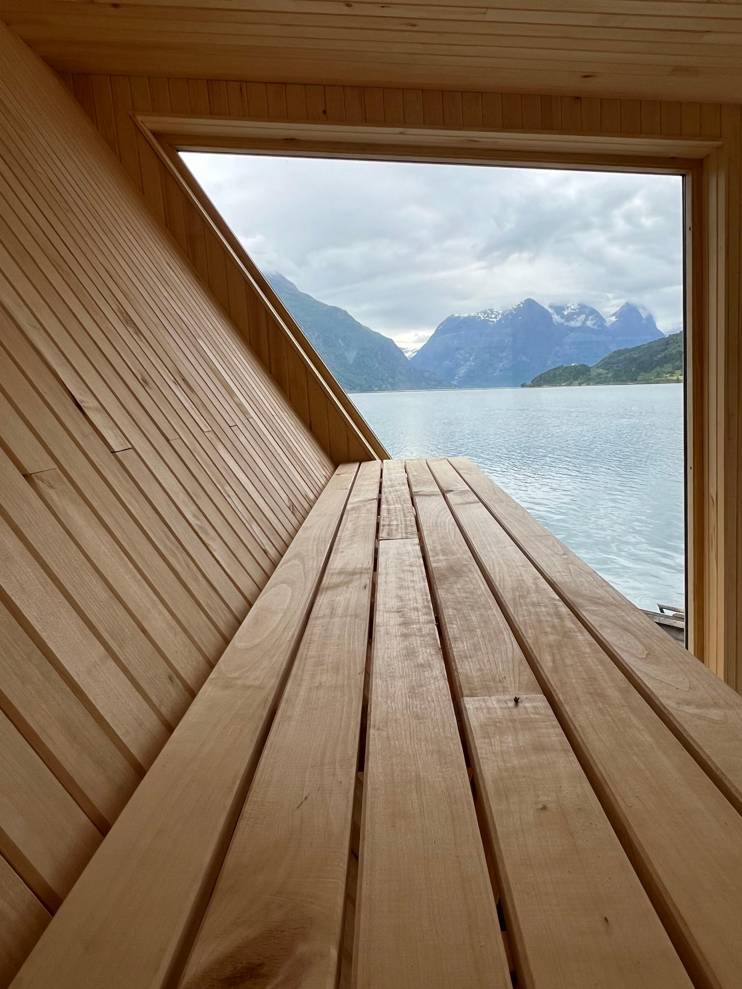Frå benkane i Lidasanden Floating Sauna får du panoramautsikt over Oppstrynsvatnet og fjella rundt.