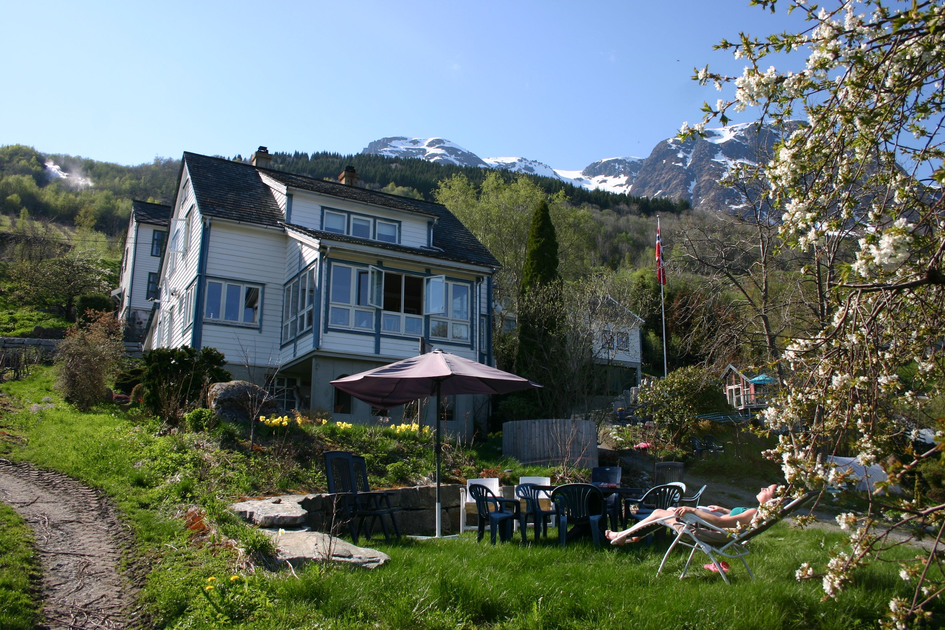Garden and outdoor seating area at Hardanger Harmoni Fjordhus overlooking mountains and fjord.