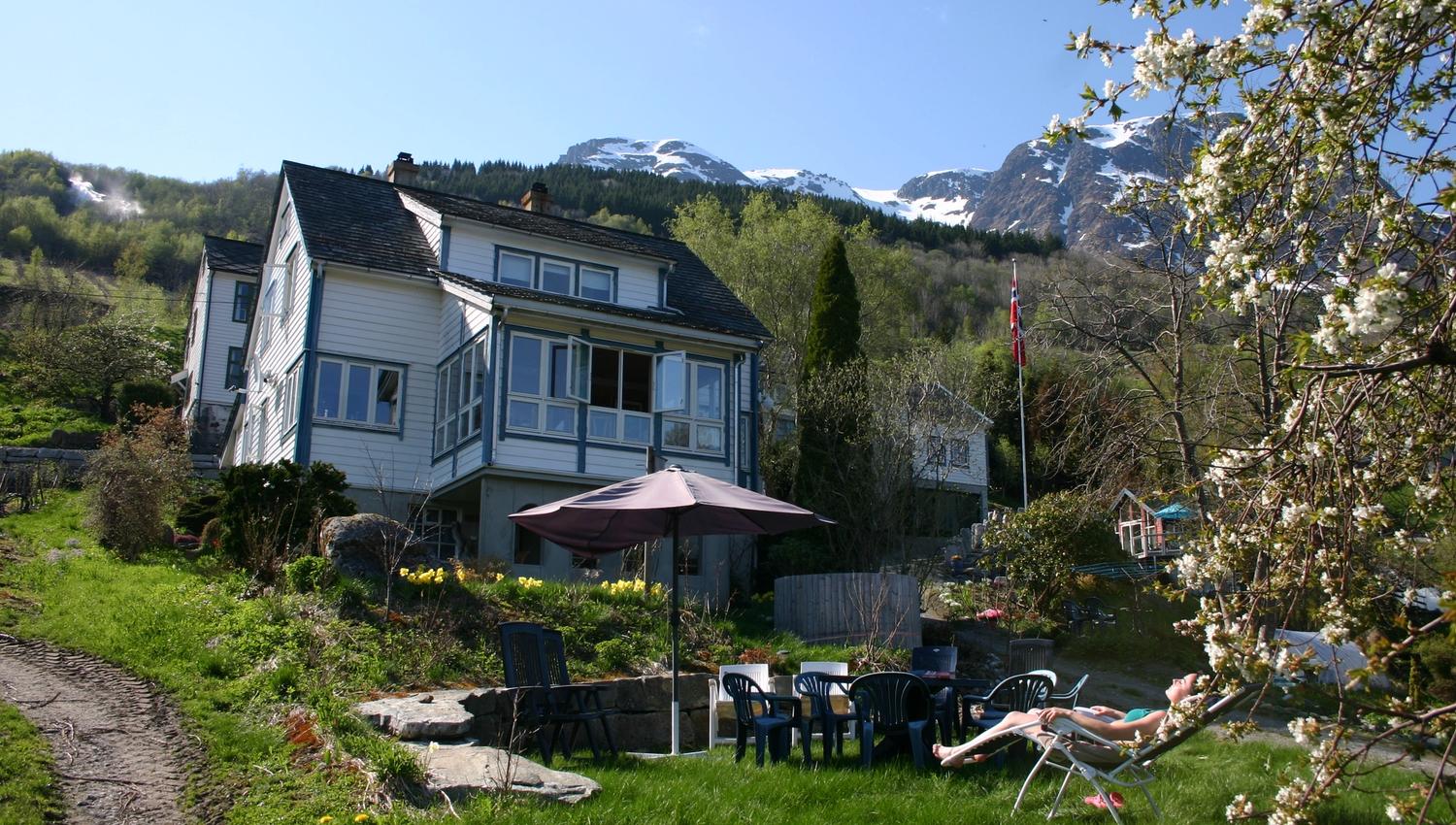 Garden and outdoor seating area at Hardanger Harmoni Fjordhus overlooking mountains and fjord.