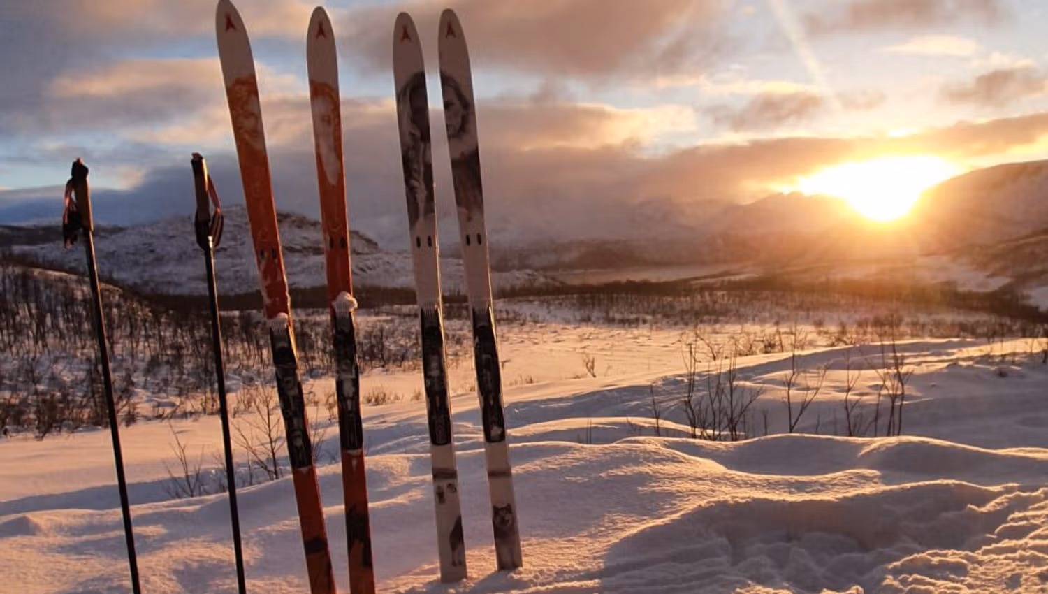 Ski og staver står klar i snøen mens solen skinner