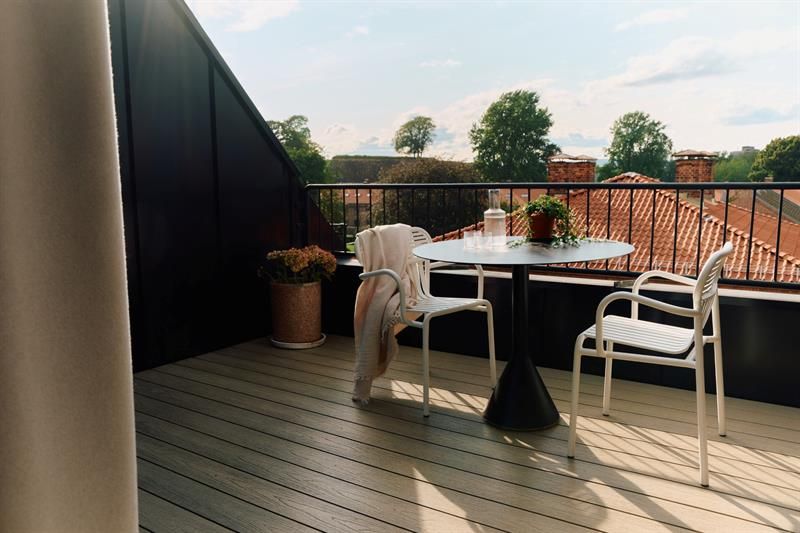 The balcony is furnished with a table and chairs and faces the surrounding buildings. It provides guests with private outdoor space.