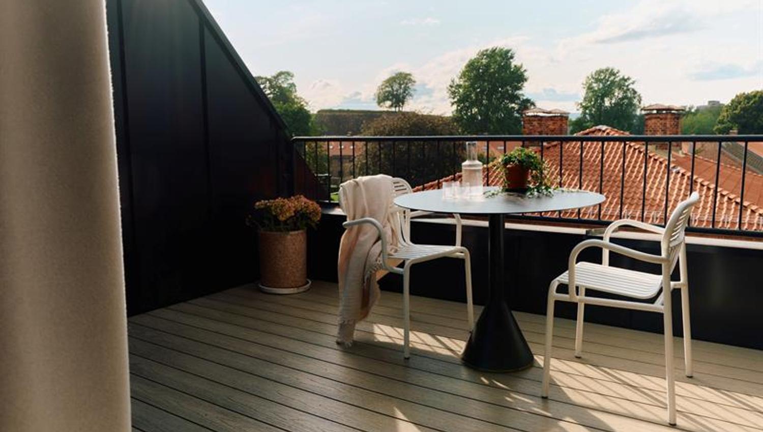 The balcony is furnished with a table and chairs and faces the surrounding buildings. It provides guests with private outdoor space.