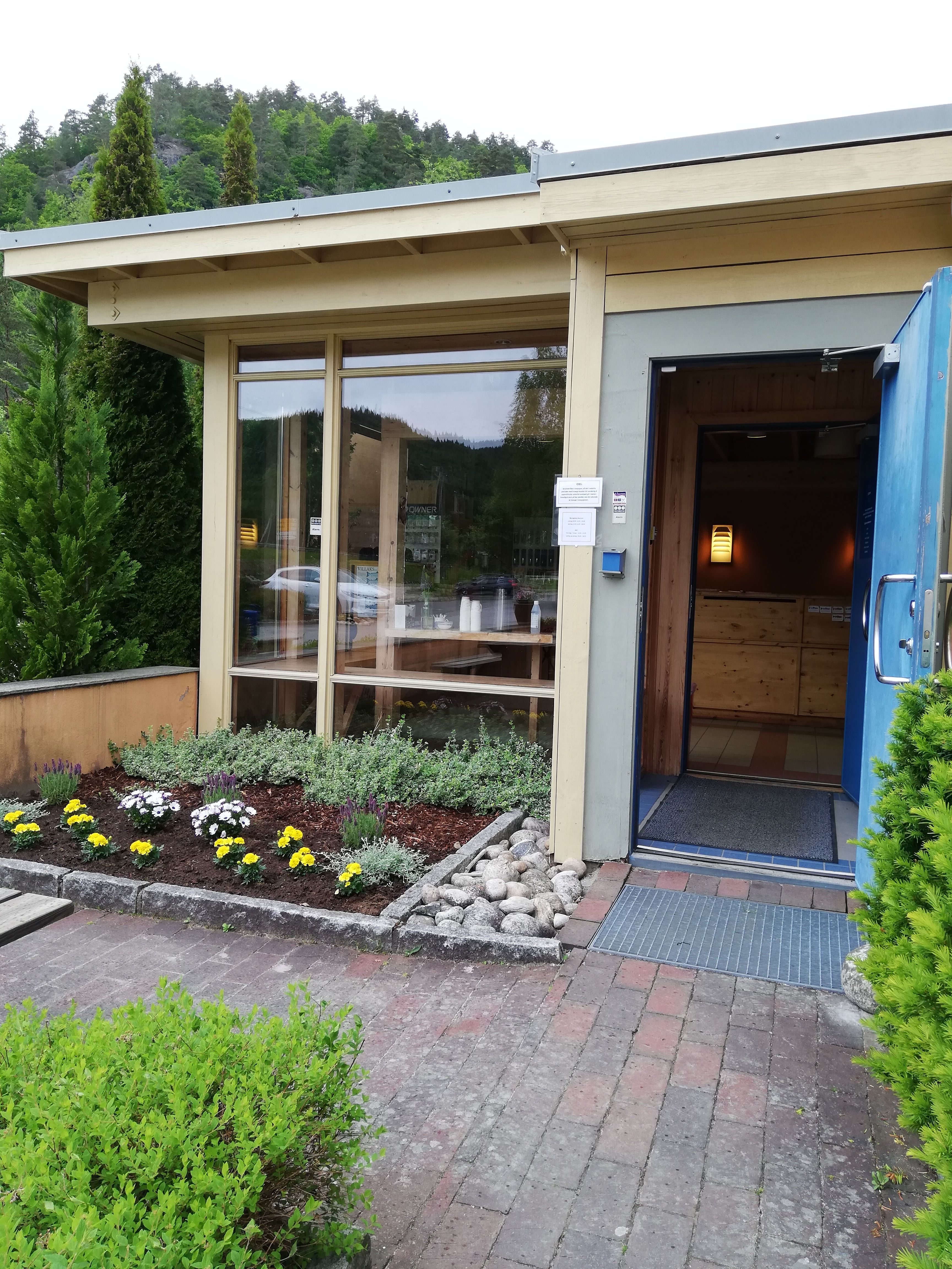 Fassade des Wildlachs-Besucherzentrums in Laudal mit Eingangsbereich und offener Tür.