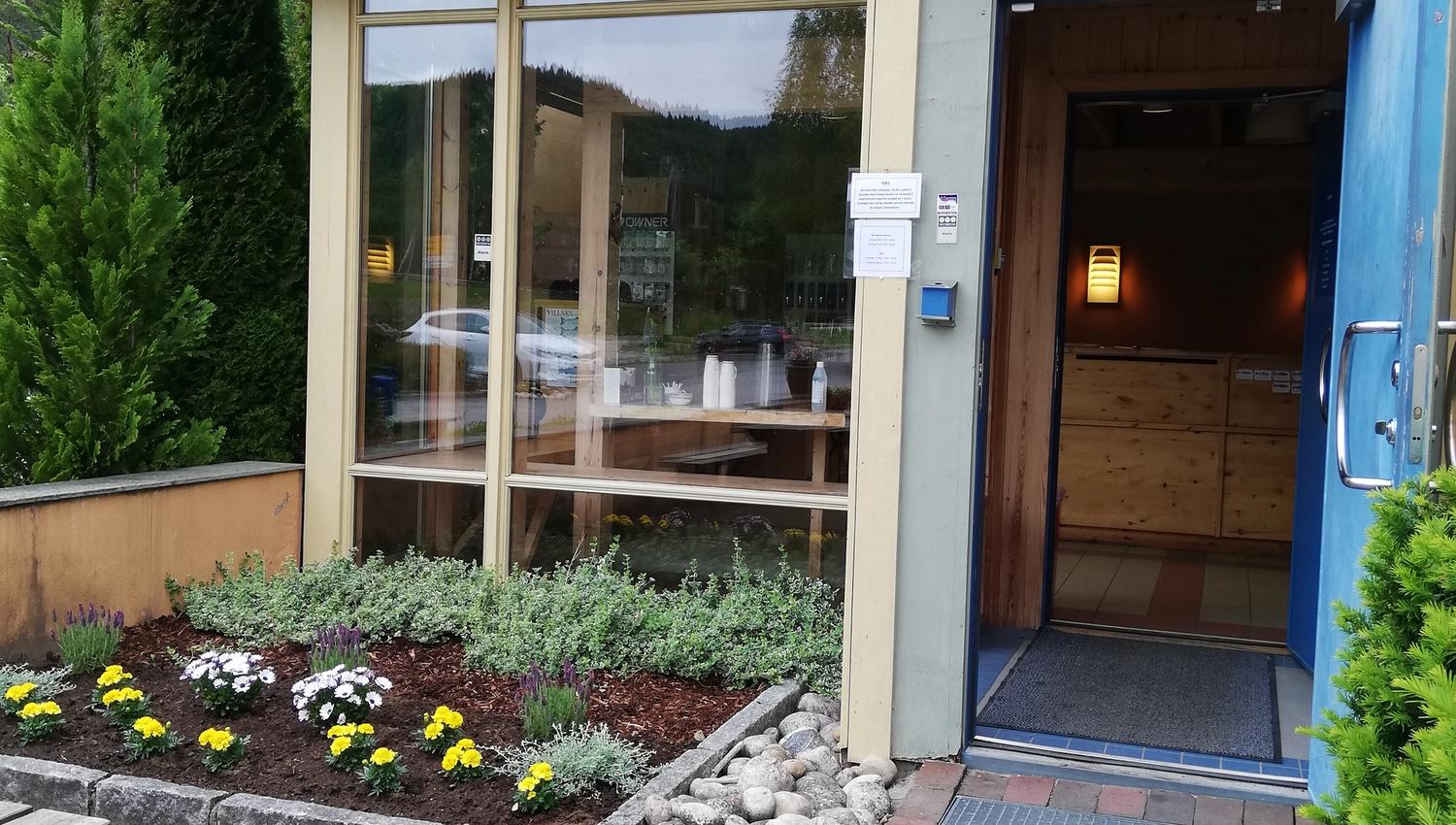 Fassade des Wildlachs-Besucherzentrums in Laudal mit Eingangsbereich und offener Tür.